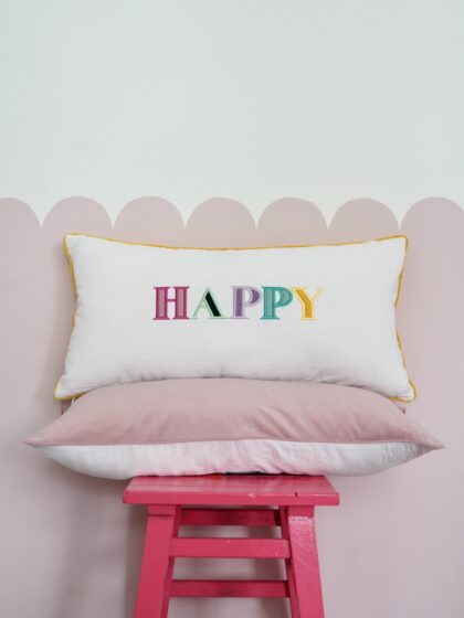 Decorative pillowcase with a colorful embroidered inscription "Happy"