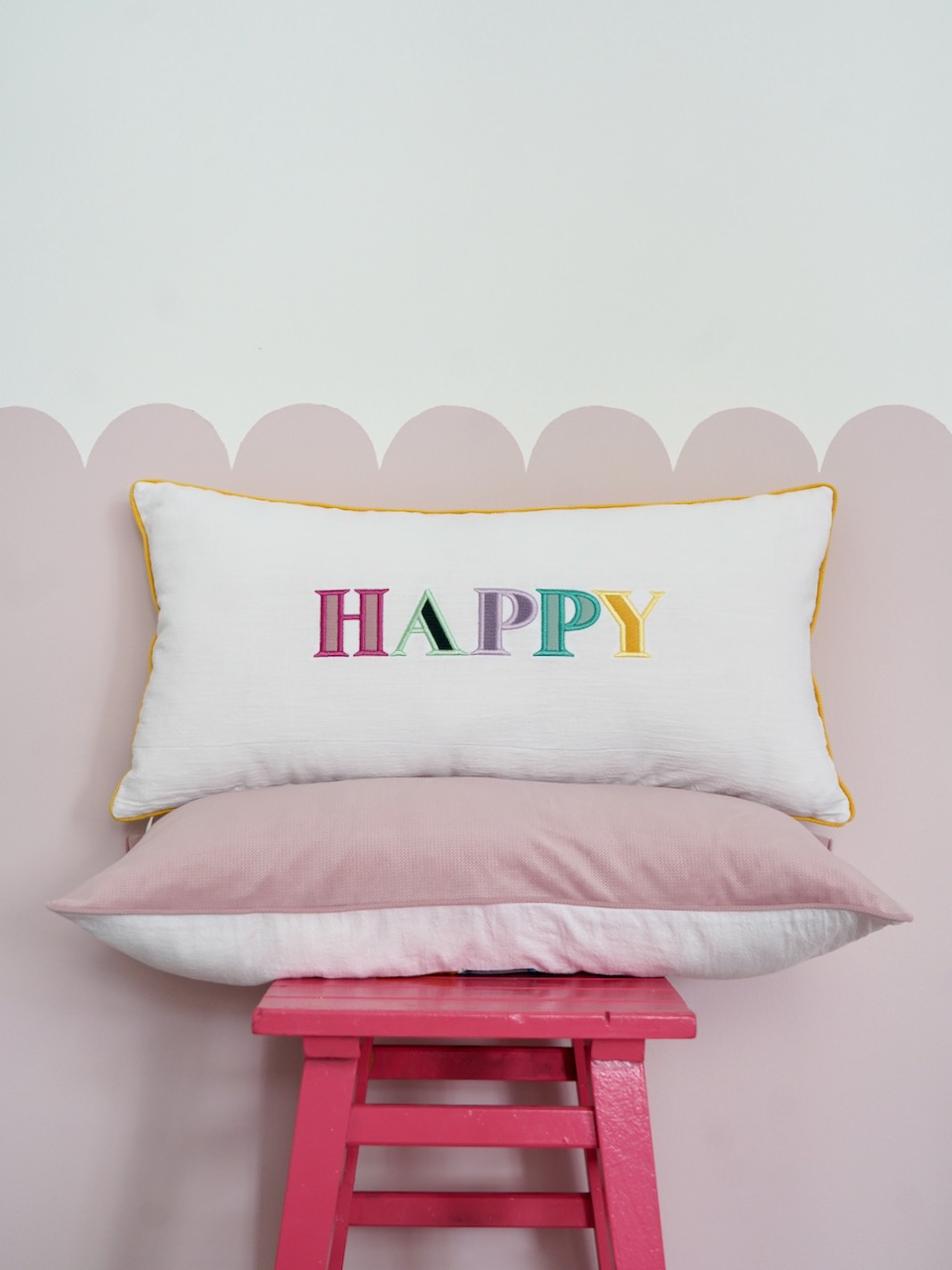Decorative pillowcase with a colorful embroidered inscription "Happy"